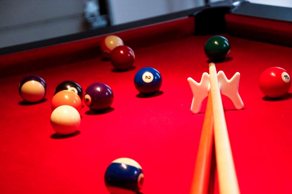 Boules et queue de billard sur le tapis rouge de la salle de jeux de La Grange d'Hélène