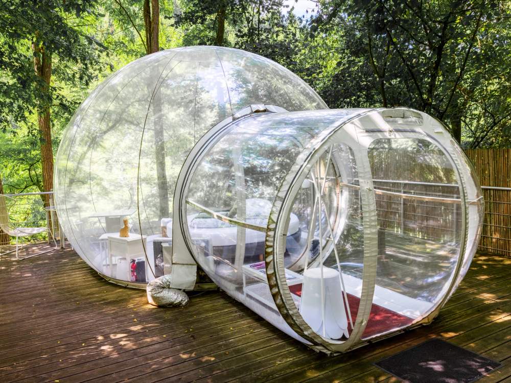 Deux bulles transparentes reliées sur une terrasse en bois, au milieu des arbres, à La Grange d'Hélène à Siersthal