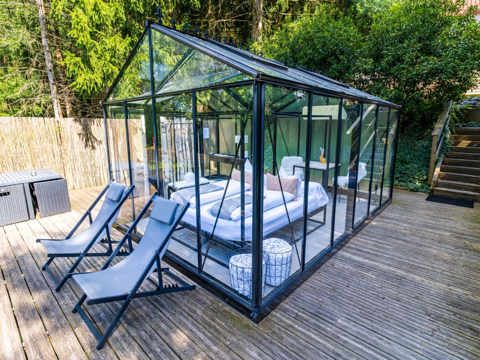 Intérieur de La Chambre de Verre avec lit double et coin bureau, parois vitrées ouvertes sur le jardin