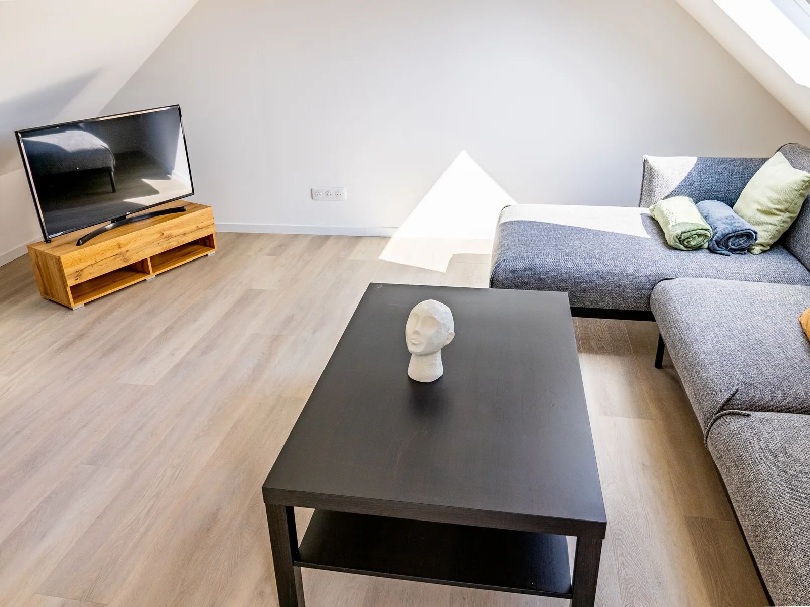 Salon mansardé de La Petite Grange avec canapé d'angle et télévision