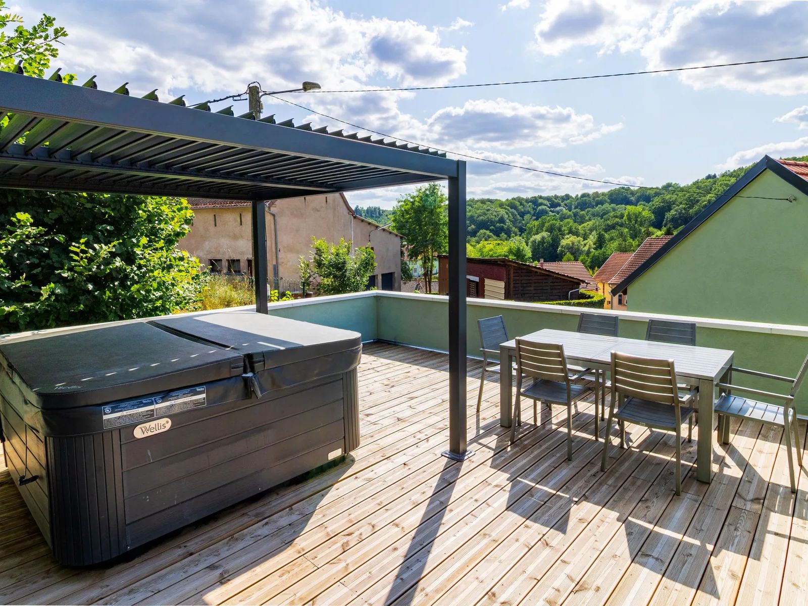 Terrasse de La Petite Grange avec spa extérieur, salon de jardin et vue sur les collines de Siersthal