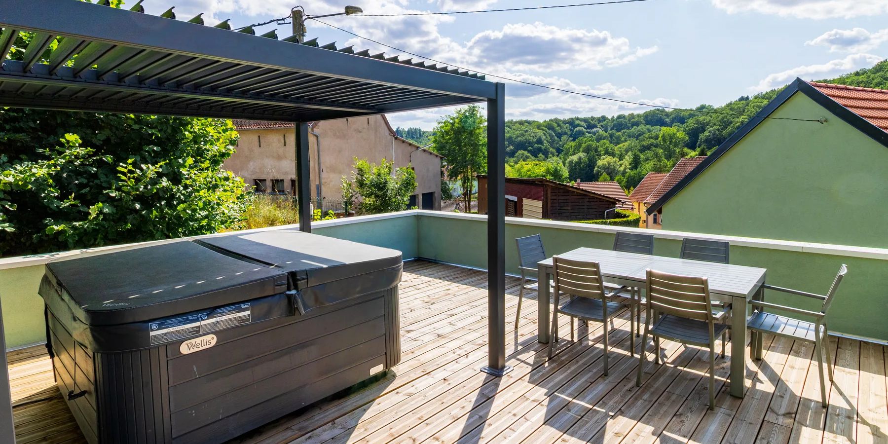 Terrasse de La Petite Grange avec spa extérieur, salon de jardin et vue sur les collines de Siersthal