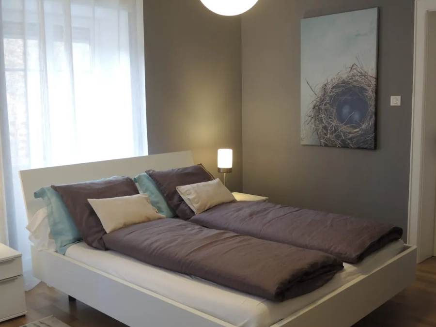 Vue d'ensemble de la chambre principale de La Suite, avec lit double et décoration gris bleuté