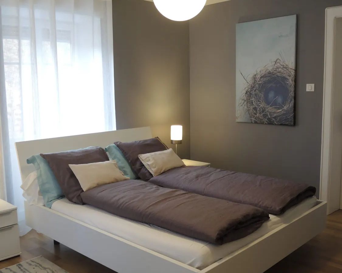 Vue d'ensemble de la chambre principale de La Suite, avec lit double et décoration gris bleuté