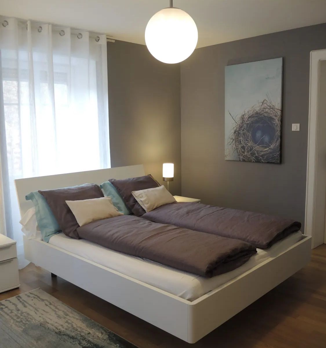 Vue d'ensemble de la chambre principale de La Suite, avec lit double et décoration gris bleuté
