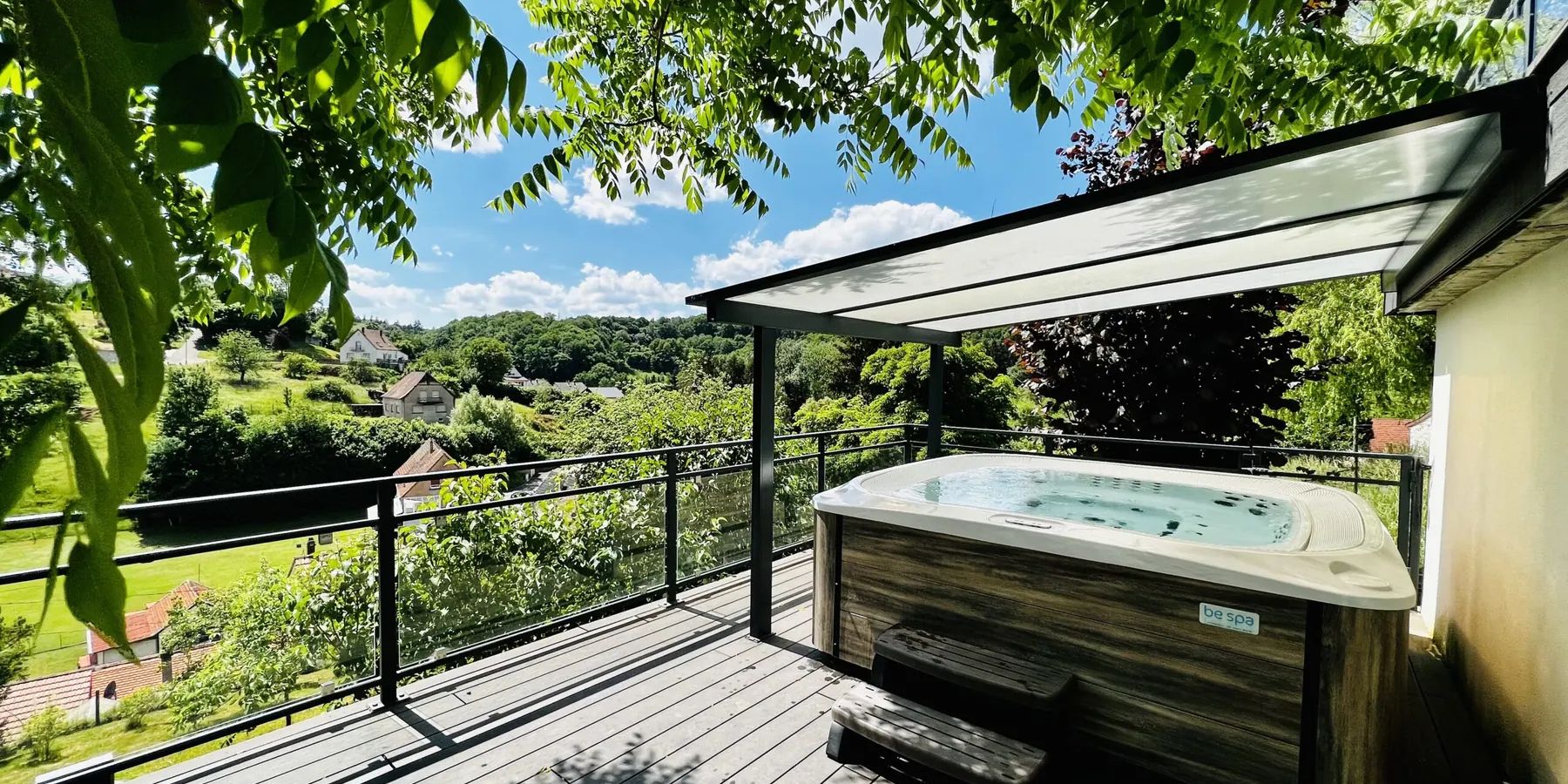 Jacuzzi extérieur du Gîte des Hauts de la Grange sur la terrasse avec vue sur la vallée