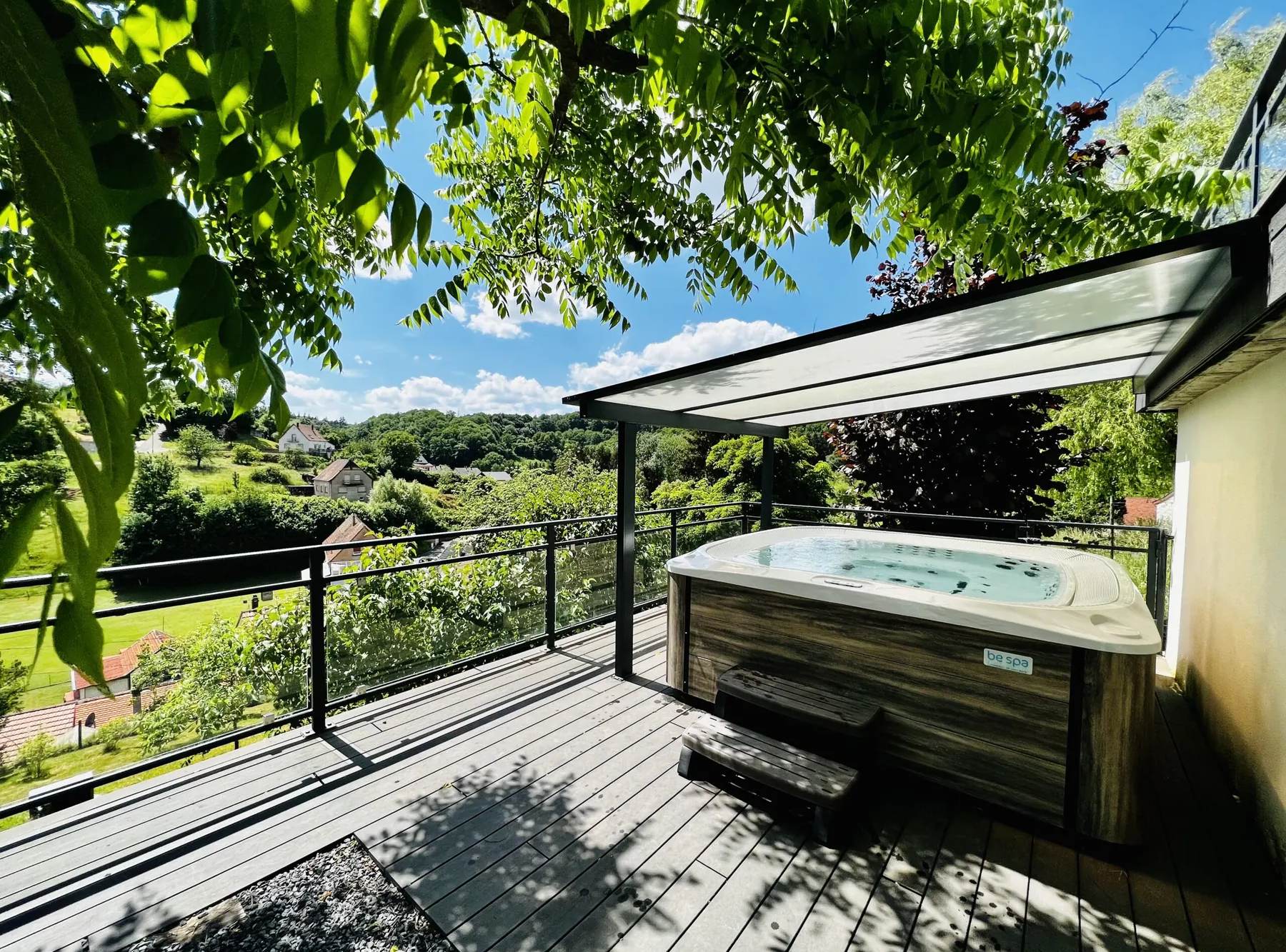 Jacuzzi privatif sur la terrasse du Gîte des Hauts de la Grange avec vue sur la vallée