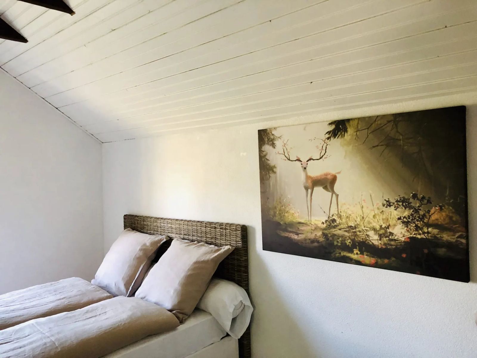 Chambre du Gîte des Hauts de la Grange avec poutres apparentes et tableau de cerf